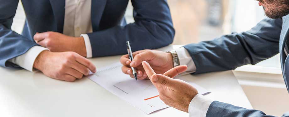 Quais são os benefícios do seguro garantia corretora? Na imagem, vemos duas pessoas firmando um contrato protegido por seguro garantia, que tem benefícios como segurança de transações comerciais