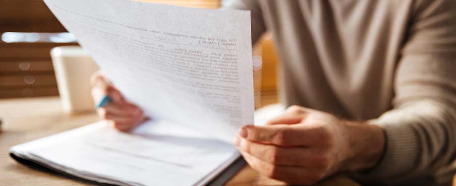 Com contratar um seguro garantia? Na imagem, dono de empresa lê contrato após fazer cotação de seguro garantia online