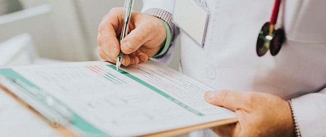 Qual o melhor seguro saúde no Brasil? Na imagem, médico preenchendo protocolo após atendimento de paciente que tem seguro saúde
