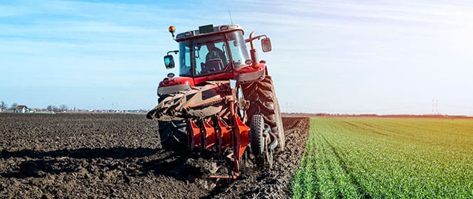 Como fazer um seguro agrícola? Na imagem, trator de agricultura passando em terra evidencia a importância do seguro para agronegócio