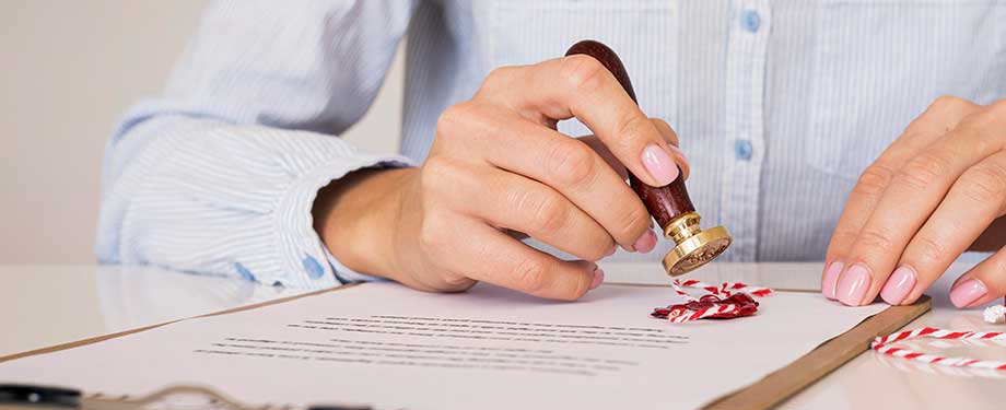 Como funciona o seguro garantia em processo judicial? Na imagem, pessoa carimbando documento, evidenciando que o seguro judicial bond garante o pagamento de indenizações judiciais