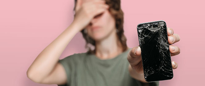 O que o seguro Iphone cobre? Na imagem, mulher segura Iphone com tela quebrada, que tem cobertura pelo seguro que contratou