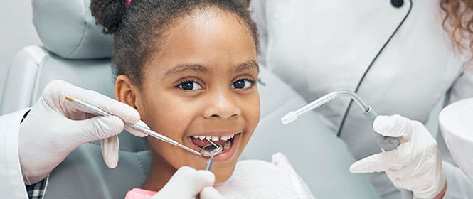 O que cobre um seguro odontológico? Na imagem, criança fazendo limpeza dentária no dentista