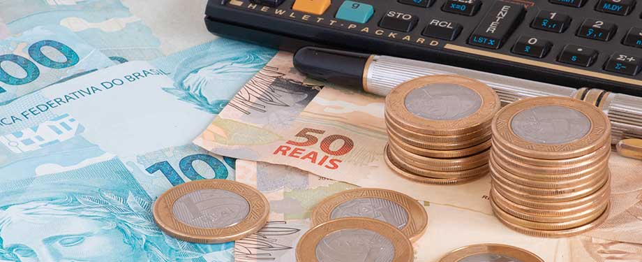 Previdência privada como funciona? Na imagem, vemos calculadora, dinheiro e caneta representando a dúvida sobre o que vale mais a pena: previdência privada, poupança ou tesouro direto