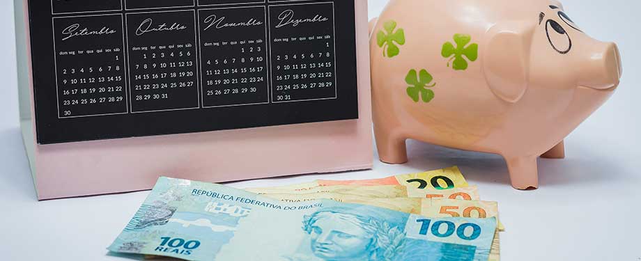 Previdência privada vale a pena? Na imagem, cofre de porquinho, notas de dinheiro e calendário em representação aos benefícios do planejamento financeiro