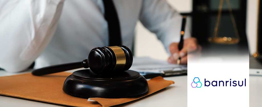 Como ver licitações do governo? Na imagem, vemos martelo da justiça e pessoa a assinando contrato de licitação com a instituição pública do Rio Grande do Sul