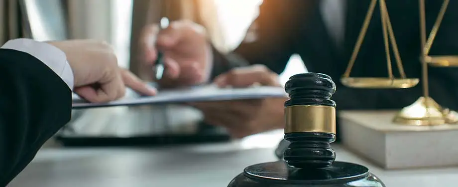 Quais sãos os tipos de responsabilidade civil? Na imagem, vemos martelo e balança da justiça e dono de empresa contratando seguro do tipo contratual