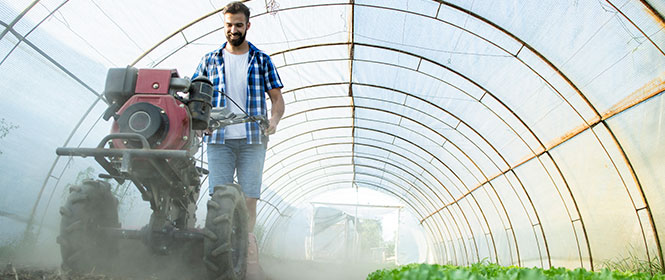 Qual a diferença entre seguro rural tradicional e o seguro paramétrico? Na imagem, vemos produtor rural trabalhando e estando coberto contra eventos climáticos