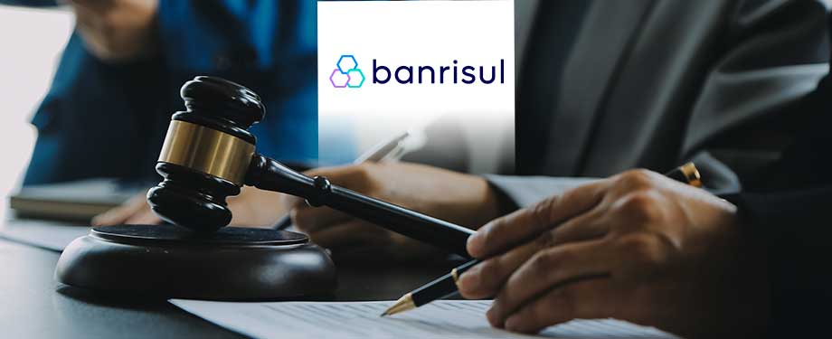 Como funcionam as licitações Banrisul? Na imagem, vemos martelo da justiça e pessoa lendo proposta de licitação, que poderá ser contemplada