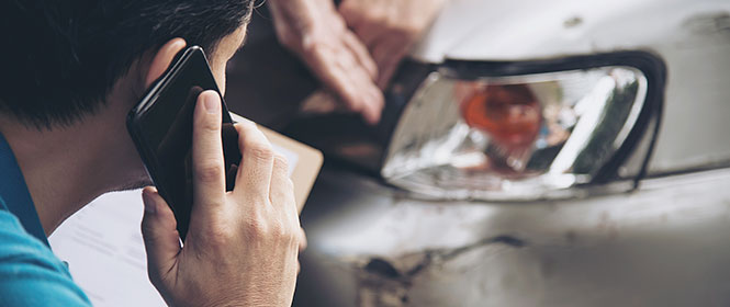 O que vem a ser sinistro? Na imagem, homem contatando seguro após imprevisto com carro, representando o significado de sinistro