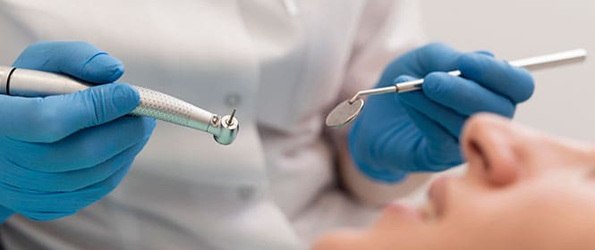 Plano odontológico preços: na imagem, dentista faz procedimento de limpeza em paciente
