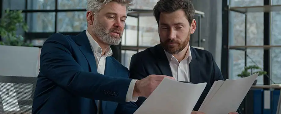 Como funciona contrato de contragarantia? Na imagem, empresários lendo contrato de exigência de CCG em emissão de apólice de seguro garantia