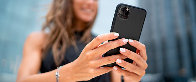 Quanto custa em média um seguro Iphone? Na imagem, mulher usando Iphone após contratar seguro