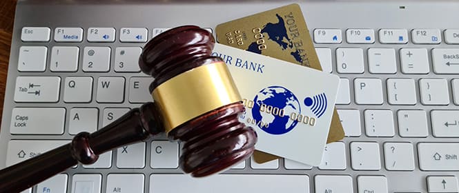 Quem paga o seguro garantia? Na imagem, martelo da justiça e cartões fazem alusão à cobrança do prêmio estabelecido no contrato do seguro licitações