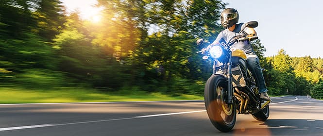 Quanto custa um seguro moto? Na imagem, homem na estrada após contratar um seguro moto online