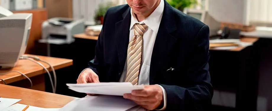 O que diz legislação sobre o seguro garantia e a fiança bancária? Na imagem, dono de empresa assinando contrato após entender o que mudou a partir de da Portaria RFB 315/2023