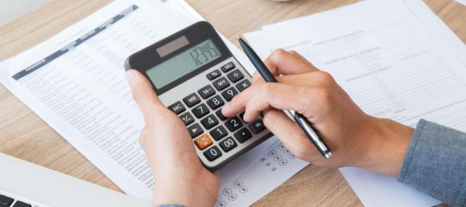 o-que-e-ICMS-sobre-o-frete? O que é ICMS sobre o frete? Na imagem, homem que sabe como calcular ICMS sobre frete fazendo isso com uma calculadora.