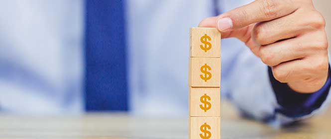 seguro-de-credito-como-funciona Quanto custa um seguro de crédito? Na imagem, pessoa empilhando quadrados que simbolizam custo do seguro de crédito