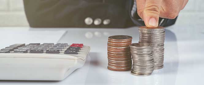 seguro-de-credito-conclusao Quais são as vantagens de contratar seguro de crédito? Na imagem, pessoa com calculadora e moedas representa a proteção financeira do seguro
